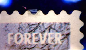 Micro Marriage proposal laser etched on glass next to a "Forever" postage stamp. 